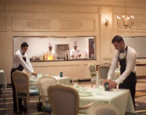 two men standing in a restaurant with tables and chefs at Sunrise Arabian Beach Resort in Sharm El Sheikh