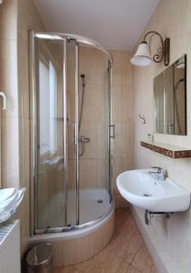 a bathroom with a shower and a tub and a sink at Hotel Zieliniec in Poznań