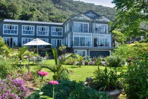 un edificio azul con un jardín delante de él en Serenity Ocean Lodge en Wilderness