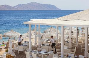 a restaurant on the beach with tables and umbrellas at Sunrise Arabian Beach Resort in Sharm El Sheikh