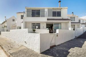 a white house with a white fence in front of it at Kleinbaai Cottage on the Sea in Cape Town