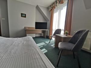 Habitación de hotel con cama, escritorio y sillas en Hotel Zieliniec en Poznan