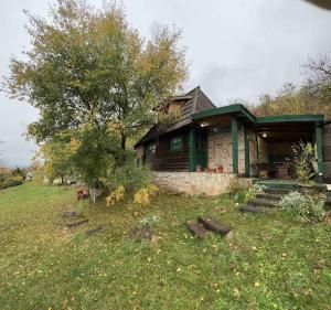 a house sitting on a grassy hill with a tree at Chalet Etno Oaza near Airport in Sarajevo