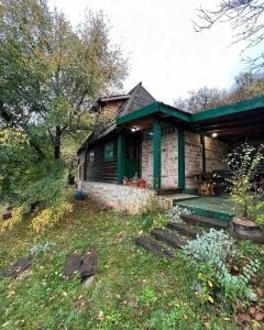 a brick house with a green roof and a porch at Chalet Etno Oaza near Airport in Sarajevo
