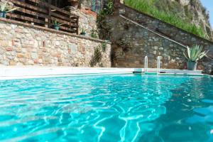 einen Pool mit blauem Wasser vor einer Steinmauer in der Unterkunft Altrove in Laterina