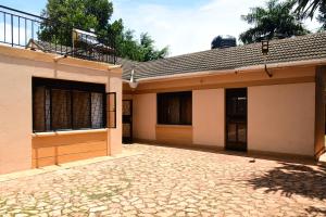 a house with a brick driveway in front of it at Golden Cherries Guest House in Jinja