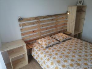 Pressagny l'OrgueilleuxにあるLes Bouches Manonのベッドルーム1室(木製ヘッドボードとテーブル付きのベッド1台付)