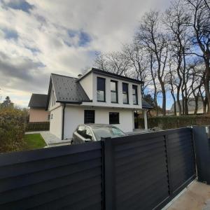ein weißes Haus mit einem schwarzen Zaun und einem Auto in der Unterkunft City house with garden, free parking in Graz