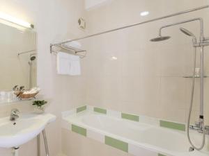 a white bathroom with a sink and a shower at Meraki Hotel in Ho Chi Minh City