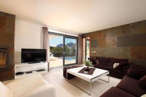 Una sala de estar con un sofá y un televisor. en Villa Cavall, en Cala de Sant Vicent
