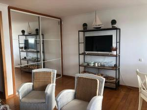 a living room with two chairs and a television at Vistas de La Barquera in San Vicente de la Barquera