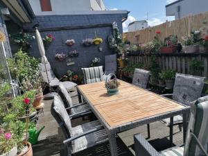 une table et des chaises en bois dans une arrière-cour ornée de plantes en pot dans l'établissement Penthousewohnung 126 qm Bremen Innenstadt+ Dachterrasse, à Brême