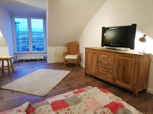 ein Wohnzimmer mit einem Flachbild-TV auf einer Holzkommode in der Unterkunft Penthousewohnung 126 qm Bremen Innenstadt+ Dachterrasse in Bremen