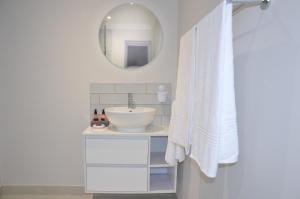 a white bathroom with a sink and a mirror at Serenity Ocean Lodge in Wilderness