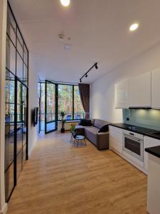 uma cozinha em plano aberto e sala de estar com um sofá em Apartamenty nad Zalewem Zegrzynskim z tarasem 23 m2 em Serock