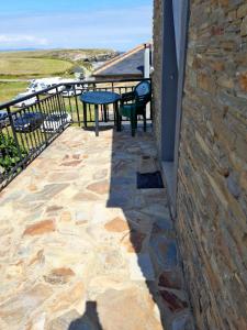 a patio with a table and chairs on a stone wall at Apartamento Playa de Esteiro in Ribadeo