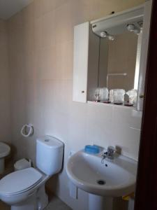 ein weißes Bad mit einem WC und einem Waschbecken in der Unterkunft Apartamento Playa de Esteiro in Ribadeo
