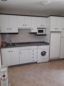 a kitchen with white cabinets and a washing machine at Apartamento Playa de Esteiro in Ribadeo