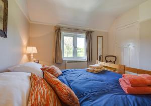 - une chambre avec un lit doté de draps bleus et une fenêtre dans l'établissement Penhill Cottage, à Saint Michaels