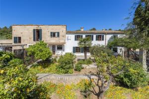 a house in the middle of a garden with trees at Es Garroverar in Pollença