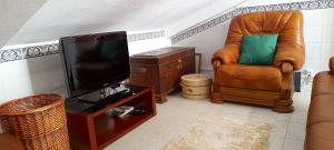 sala de estar con silla y TV de pantalla plana en Casa da Forja, en Pinhal Novo