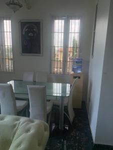 une salle à manger avec une table et des chaises en verre dans l'établissement Modern Bungalow in Idi Aba, à Abeokuta