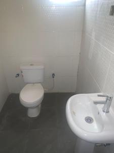 a white bathroom with a toilet and a sink at Modern Bungalow in Idi Aba in Abeokuta
