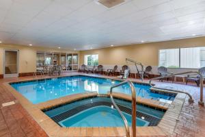 a pool in a hotel with tables and chairs at Comfort Suites Florence Shoals Area in Florence