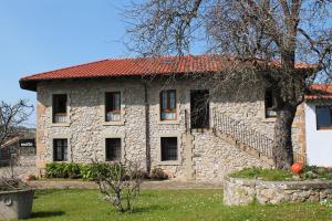 an old stone house with a red roof at Apartamentos Maite in Oreña