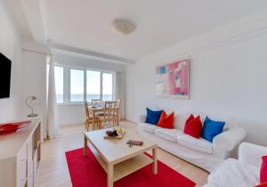 sala de estar con sofá blanco y almohadas rojas y azules en St Margarets Flat, en Rottingdean