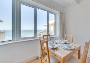 a dining room with a table and chairs with a view of the ocean at St Margarets Flat in Rottingdean