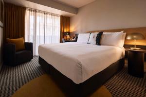 Pokój hotelowy z dużym łóżkiem i krzesłem w obiekcie The Capitol Hotel Sydney w mieście Sydney