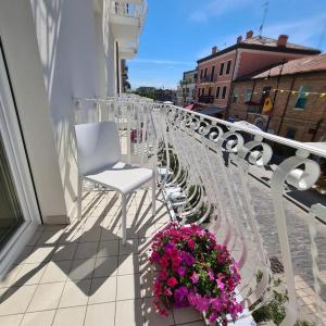 un balcone con sedie bianche e fiori su un edificio di Borgomare Camere e Colazioni a Cervia