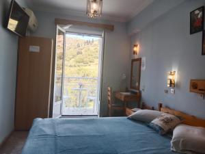 ein Schlafzimmer mit einem blauen Bett und einem großen Fenster in der Unterkunft Sandalis Hotel in Pythagoreio