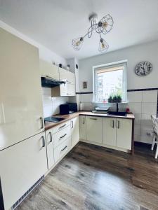a kitchen with white cabinets and a window at AL-Dom Apartamenty Apartament Anioł in Kołobrzeg