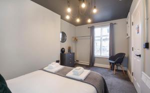 1 dormitorio con 2 camas, silla y ventana en Bateman, modern City centre apartment sleeps 6 en York