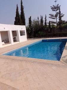uma piscina ao lado de um edifício branco e árvores em Villa Mogador em Essaouira