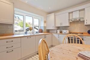 een keuken met witte kasten en een tafel en een raam bij Green Croft Coniston in Coniston
