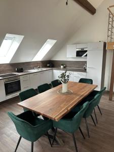 a kitchen with a wooden table and green chairs at Dachterrassenwohnung Katharinenschule in Eisenach