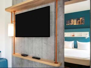 a flat screen tv on a wall in a bedroom at ibis budget Saint-Ouen-l'Aumône in Saint-Ouen-lʼAumône