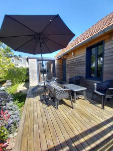 a wooden deck with a table and an umbrella at un îlot de calme in Morlaix