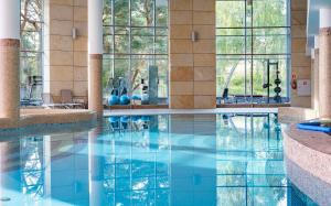 a pool in a hotel with blue water and windows at HAVET Hotel Resort & Spa in Dźwirzyno