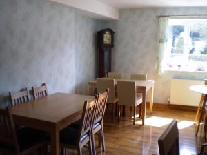 a dining room with a table and chairs and a clock at Sportsmans Lodge Bed and Breakfast in Amlwch