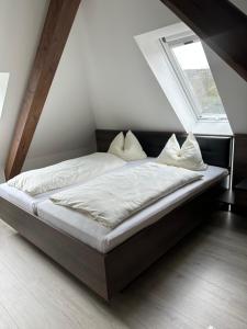a bed with white sheets and pillows in a room at Dachterrassenwohnung Katharinenschule in Eisenach
