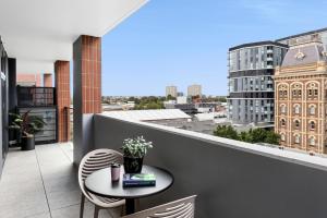 einen Balkon mit einem Tisch und Stühlen sowie Stadtblick in der Unterkunft Quest Collingwood in Melbourne