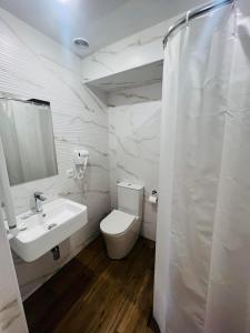 a white bathroom with a toilet and a sink at Fortune Hotel in Yerevan