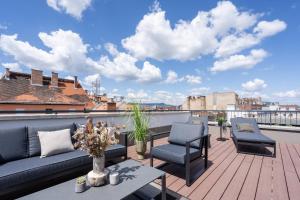 einen Balkon mit einem Sofa und Stühlen auf dem Dach in der Unterkunft The Rose Garden Apartments in Budapest