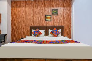 a bedroom with a white bed with a wooden wall at FabExpress Gauri Shree in Bhopal