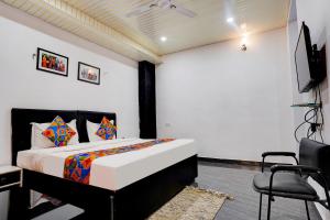 a bedroom with a bed and a tv and a chair at FabExpress Gauri Shree in Bhopal