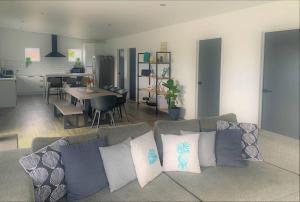 a living room with a couch with pillows and a kitchen at Bay View Bicheno in Bicheno